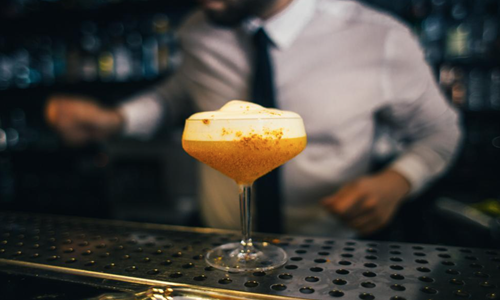 Egg-white-cocktail-on-the-bar-counter-with-bartender-in-the-background-from-Freerange.png